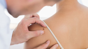 Doctor examining mole on back of woman